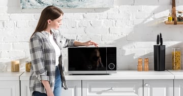 Woman with a microwave in a kitchen