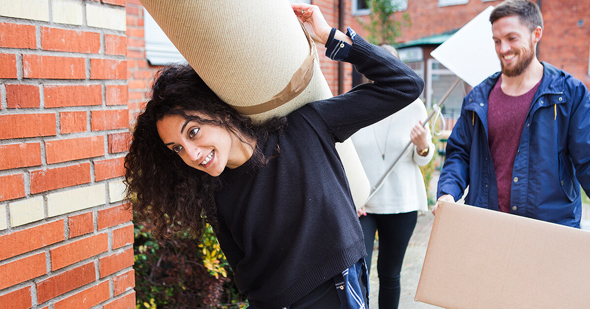 Young women moving out of home and carrying carpet