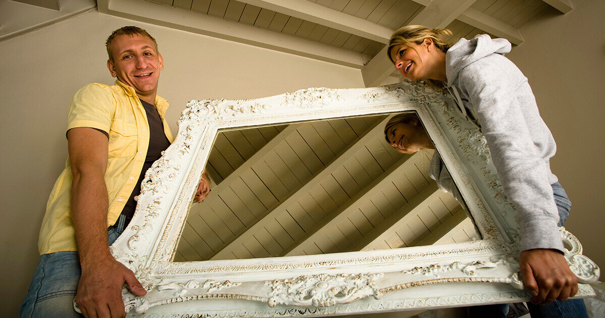 Couple moving a mirror