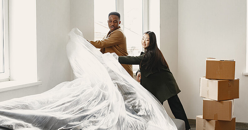 A couple putting plastic on mattress